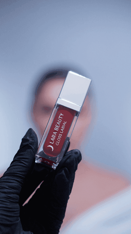 Mão enluvada segurando o gloss da linha Lara Beauty