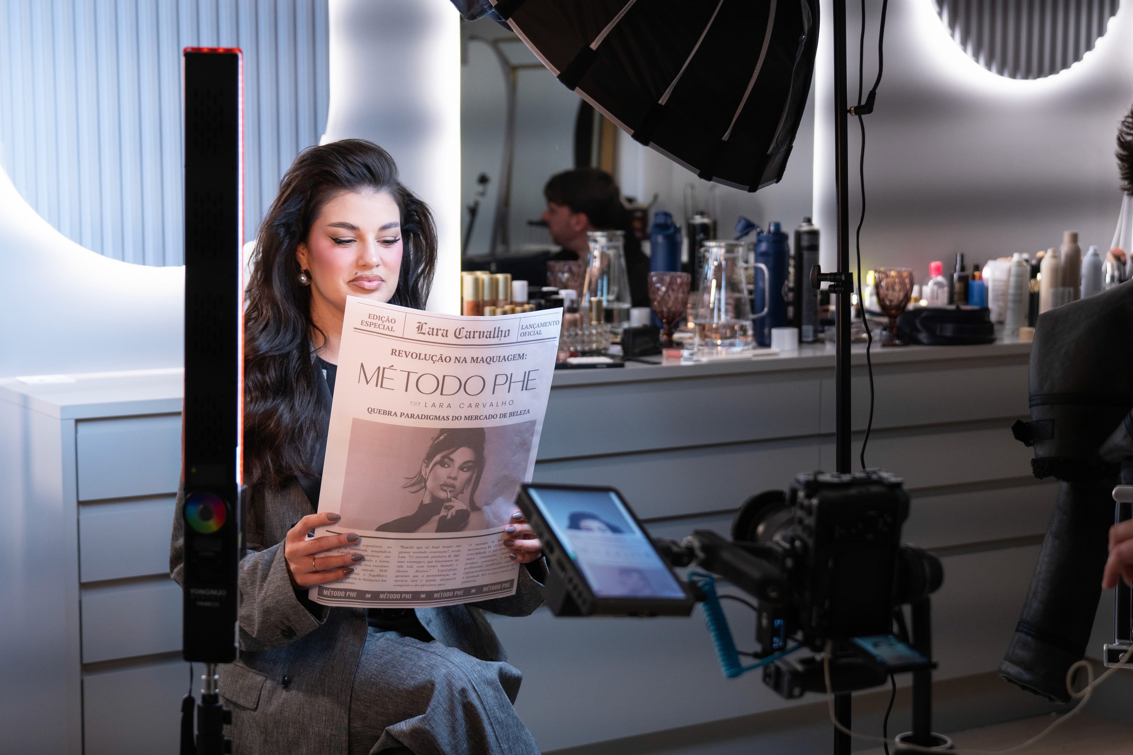 Lara lendo o jornal do Método PHE no set iluminado