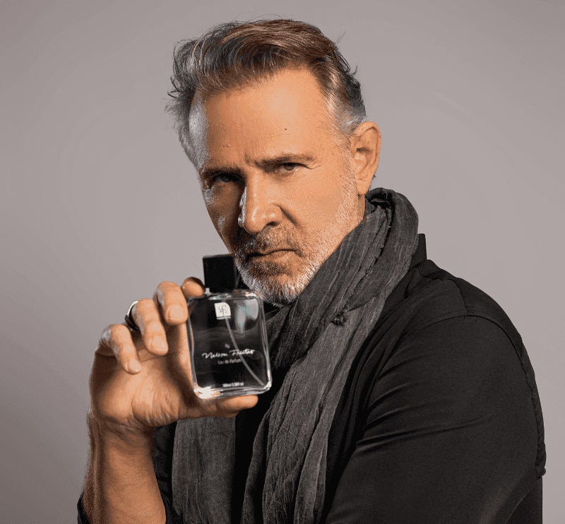 Nelson Freitas de preto segurando o frasco em retrato de estúdio