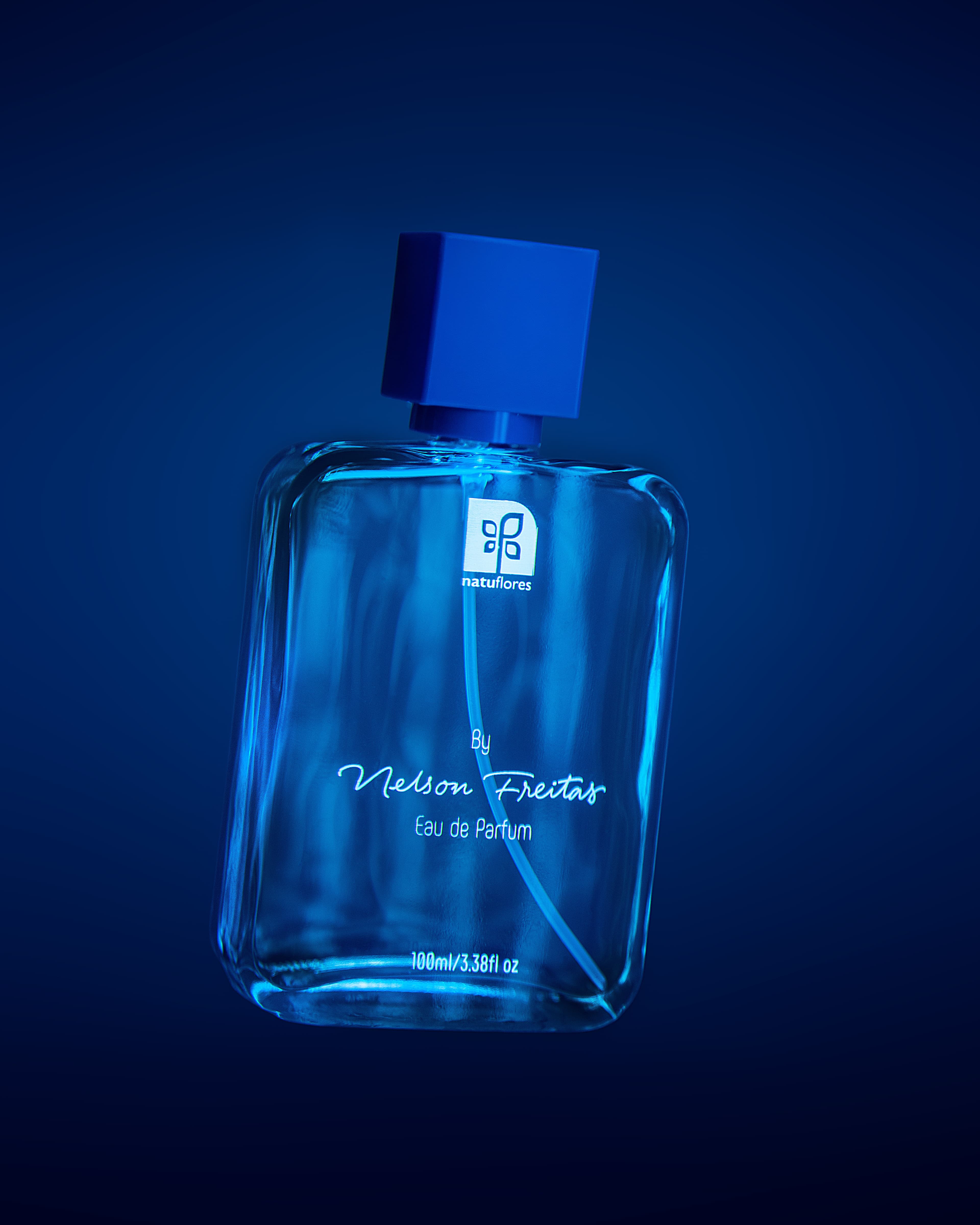 Frasco azul do perfume assinado Nelson Freitas em fundo escuro