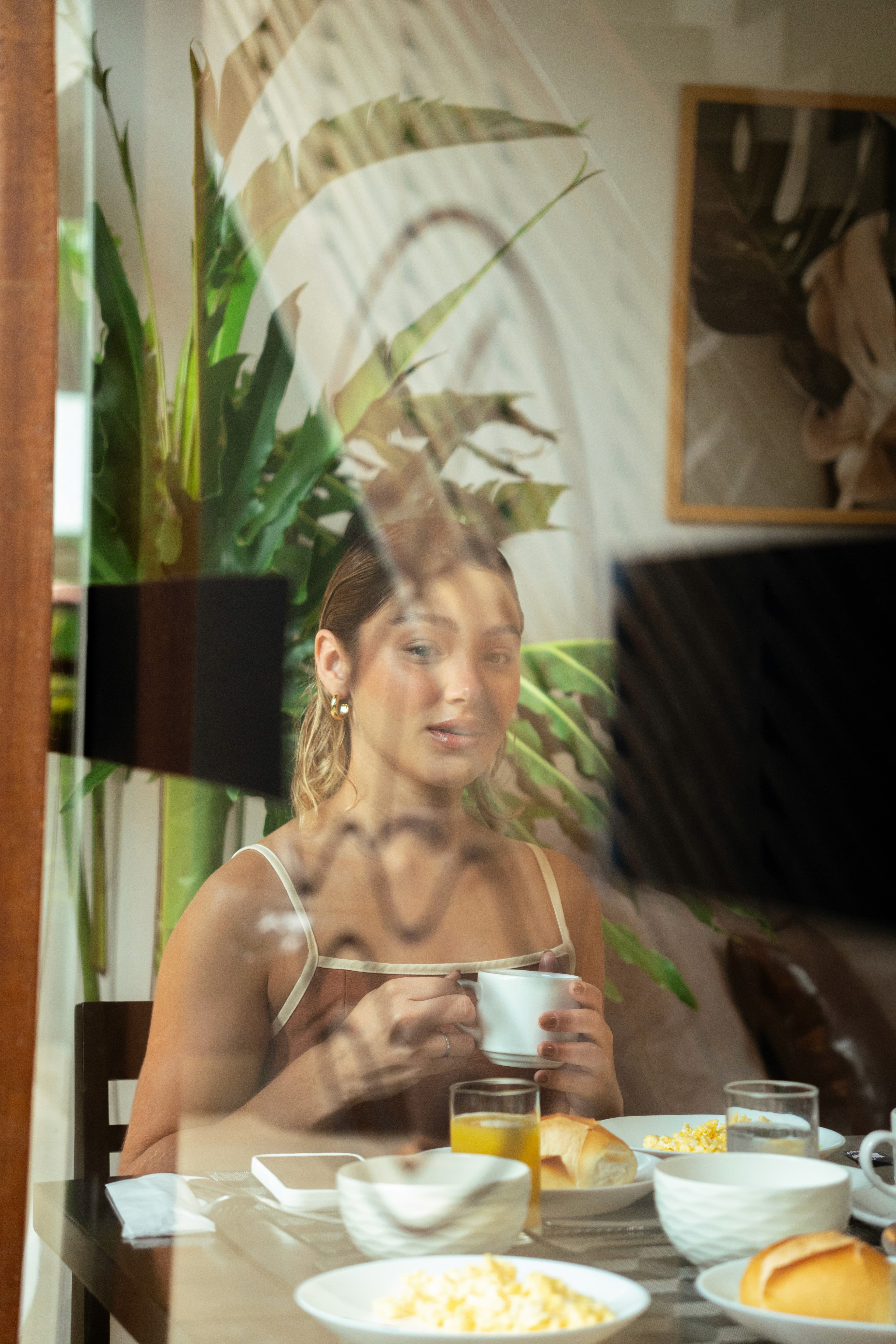 Hóspede no café da manhã, cena captada pelo reflexo do vidro