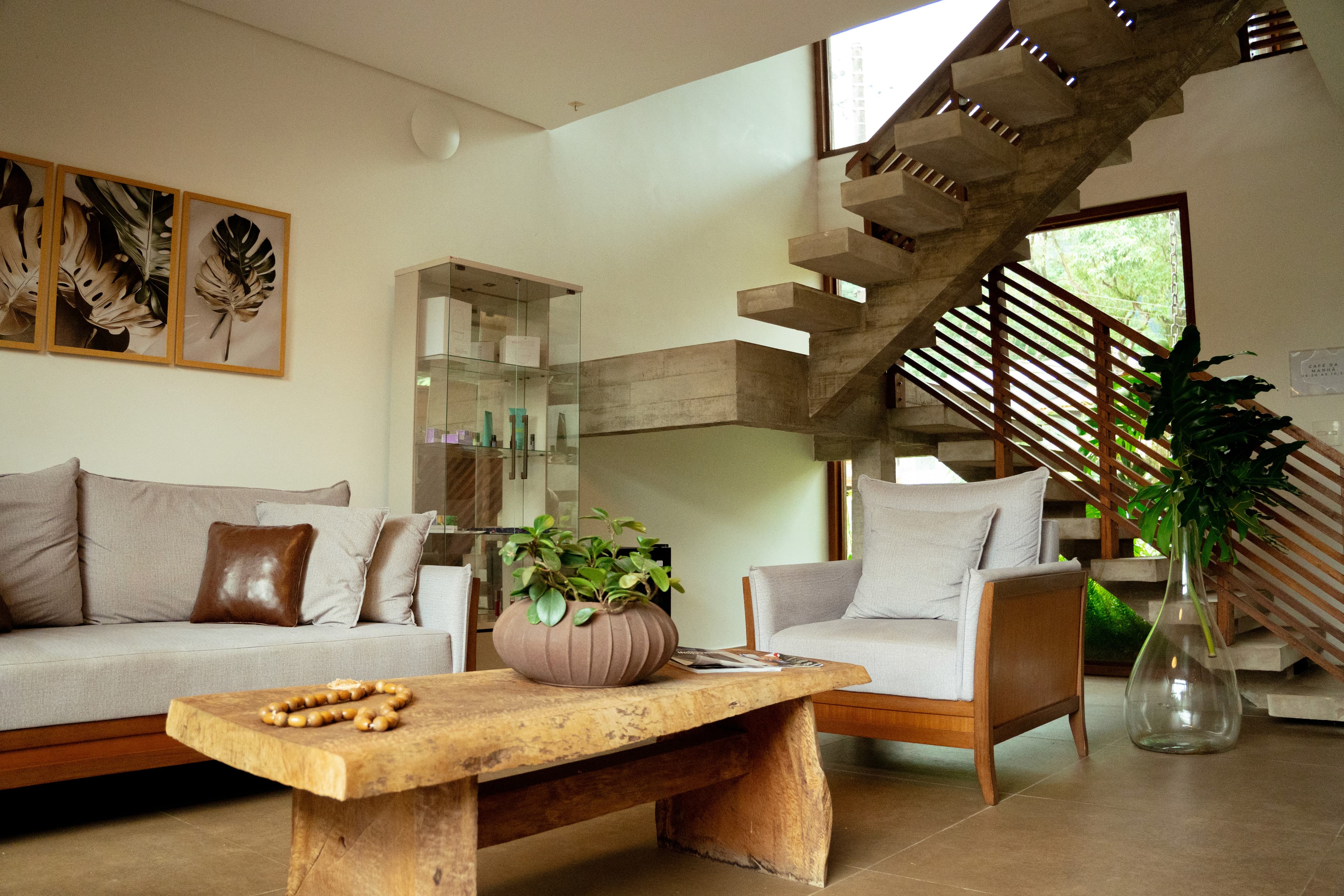 Sala de estar com escada, sofás claros e plantas
