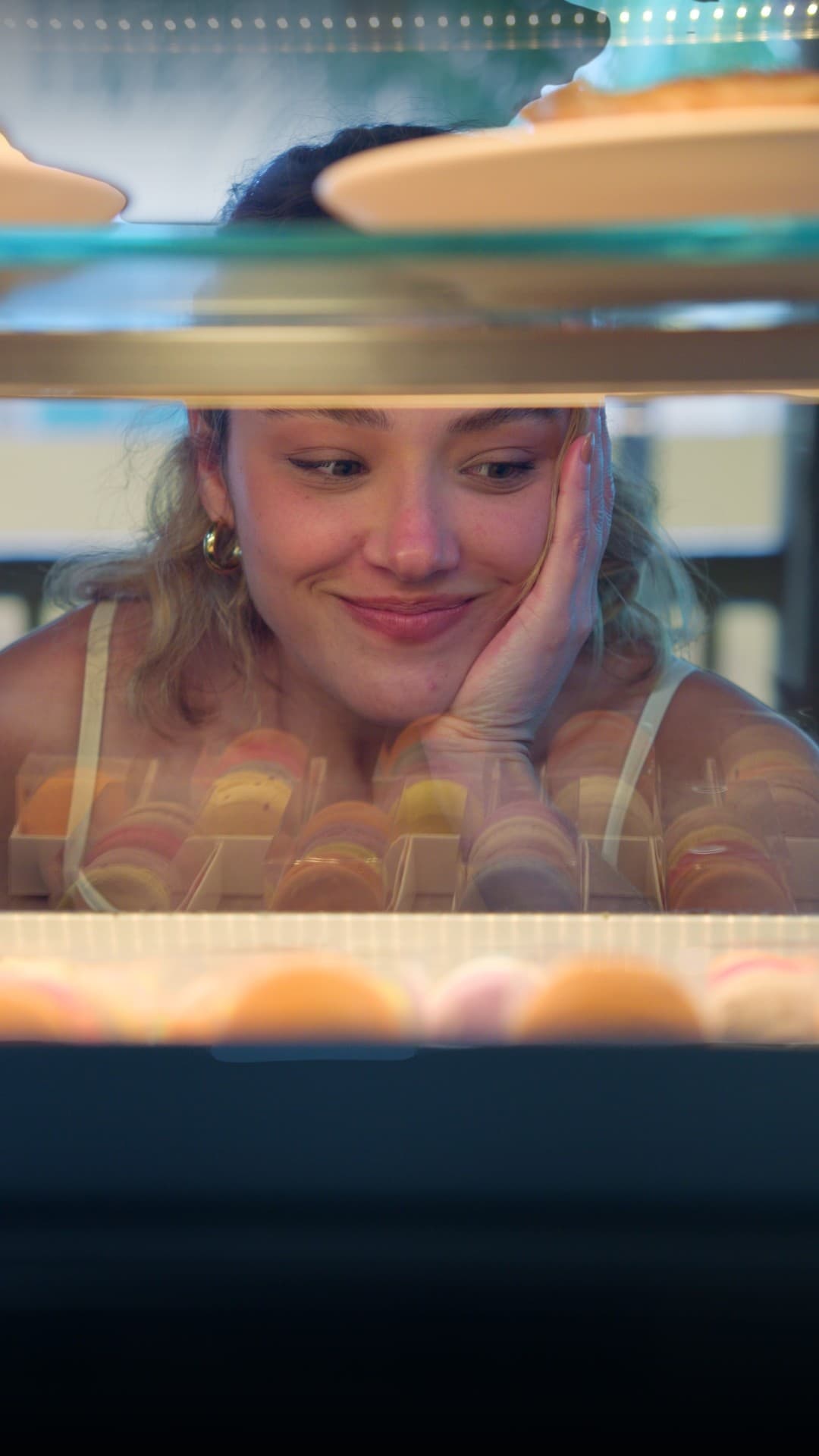 Cliente encantada olhando a vitrine de macarons