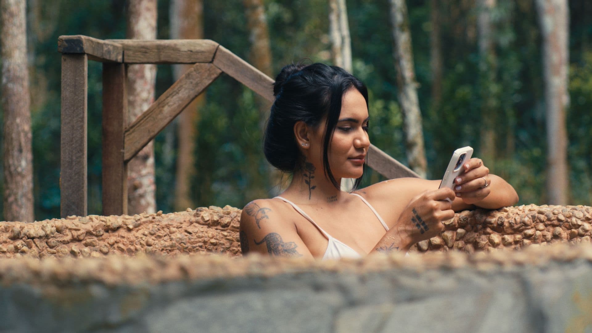 Hóspede na banheira de pedra ao ar livre olhando o celular
