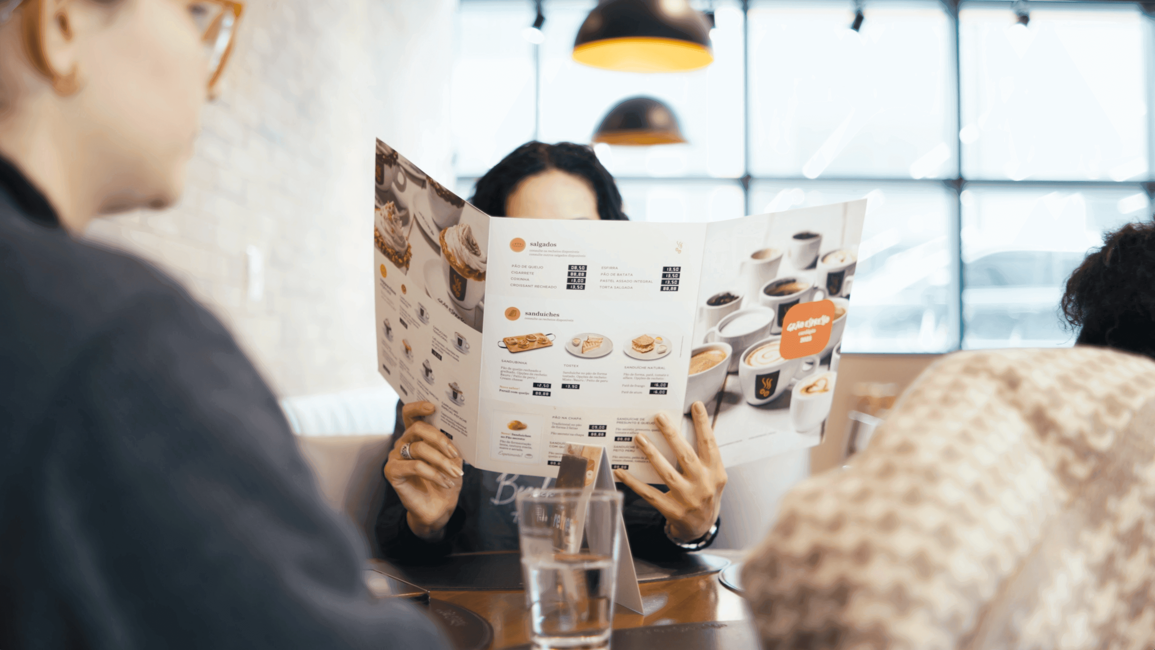 Clientes lendo o cardápio à mesa da cafeteria