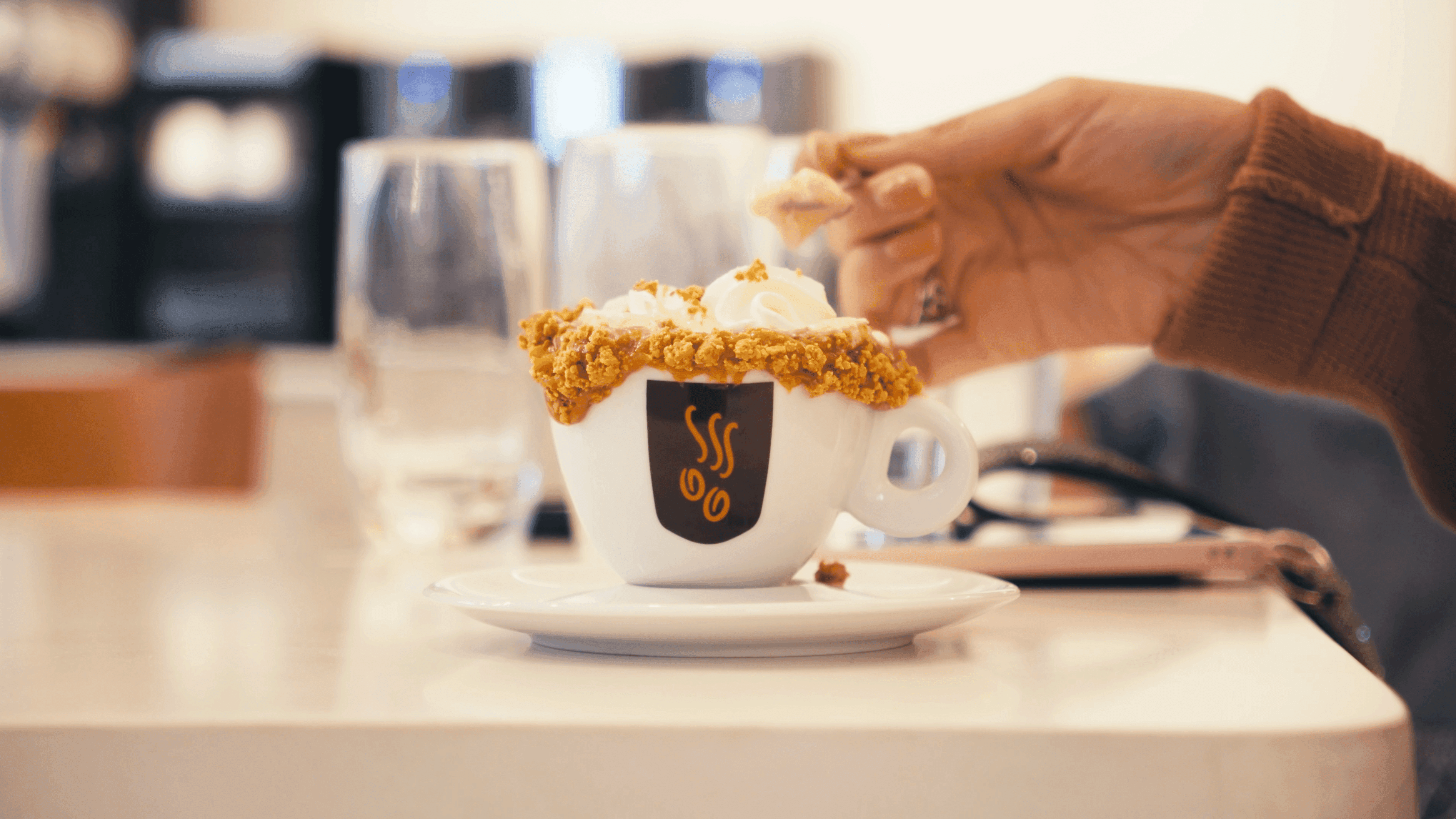 Cliente pegando o cappuccino com cobertura na xícara da marca