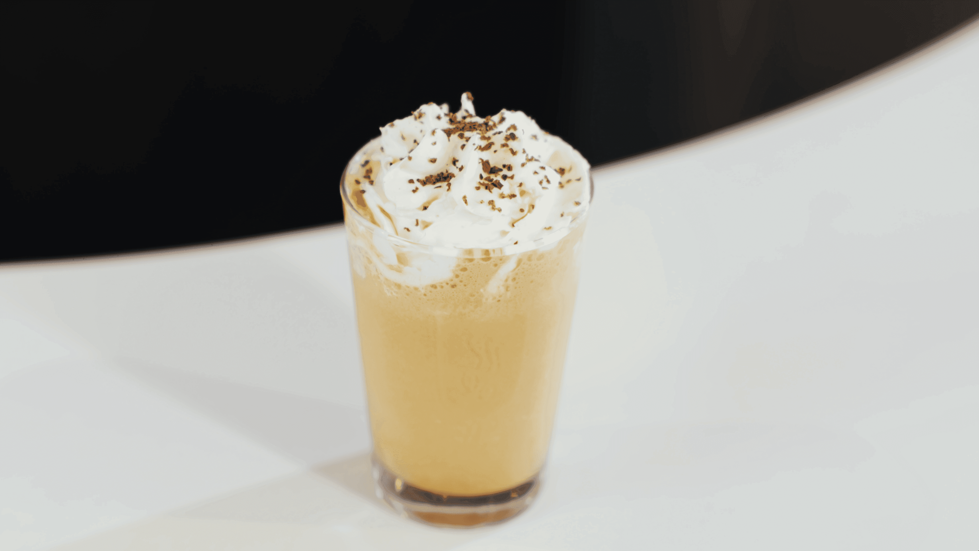 Bebida gelada com chantilly em copo sobre o balcão branco