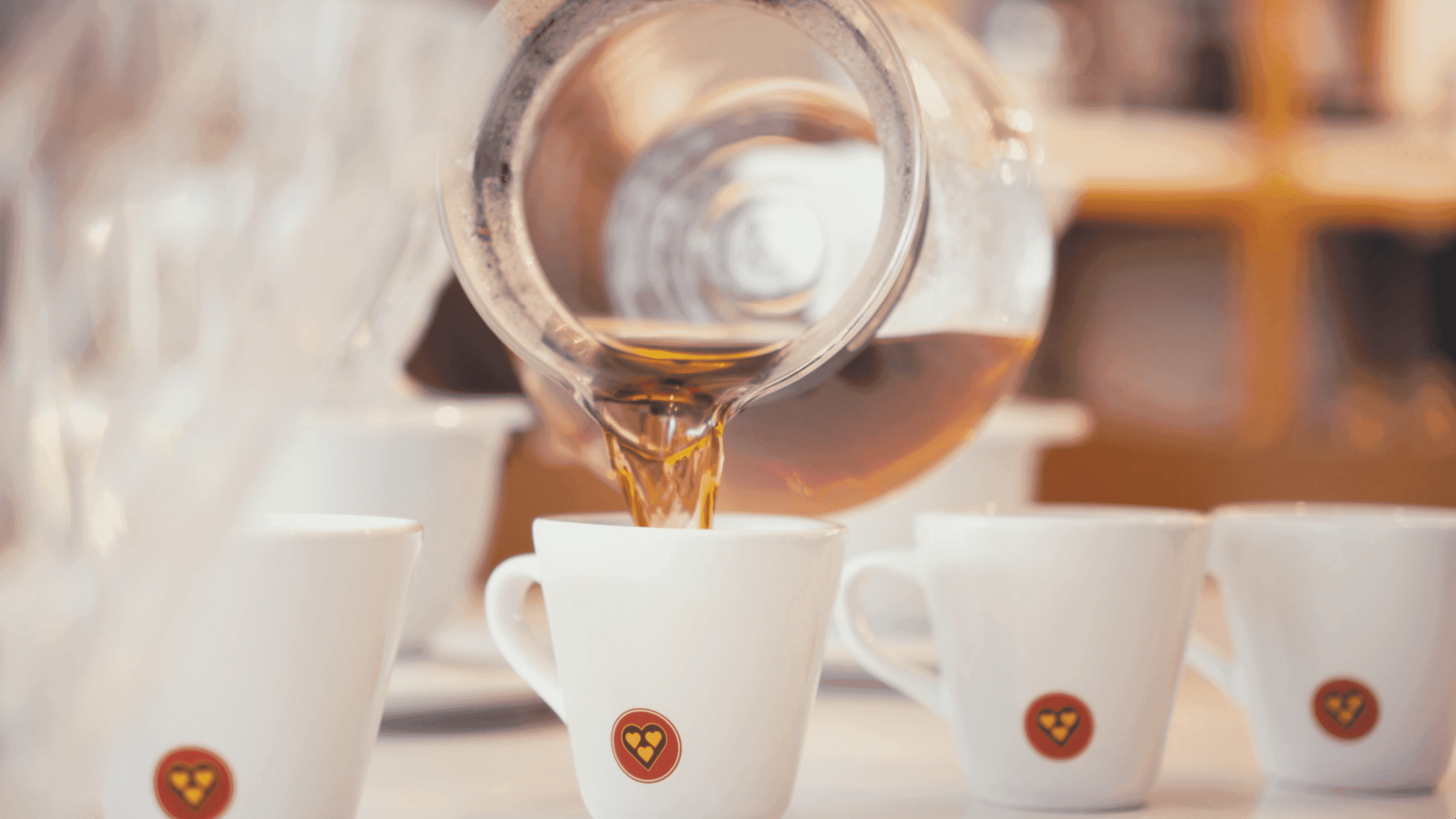 Jarra despejando café em xícaras enfileiradas